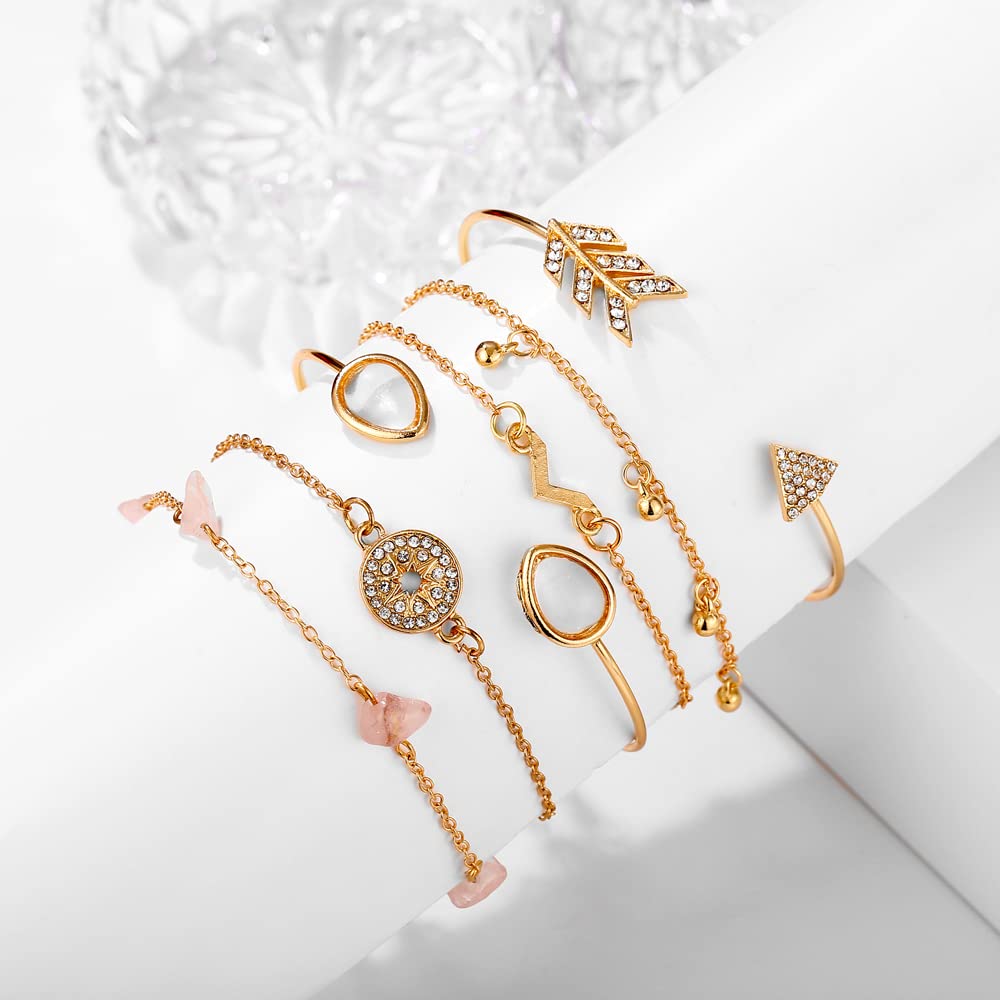 Collection of gold jewelry including bracelets and rings on a white surface.