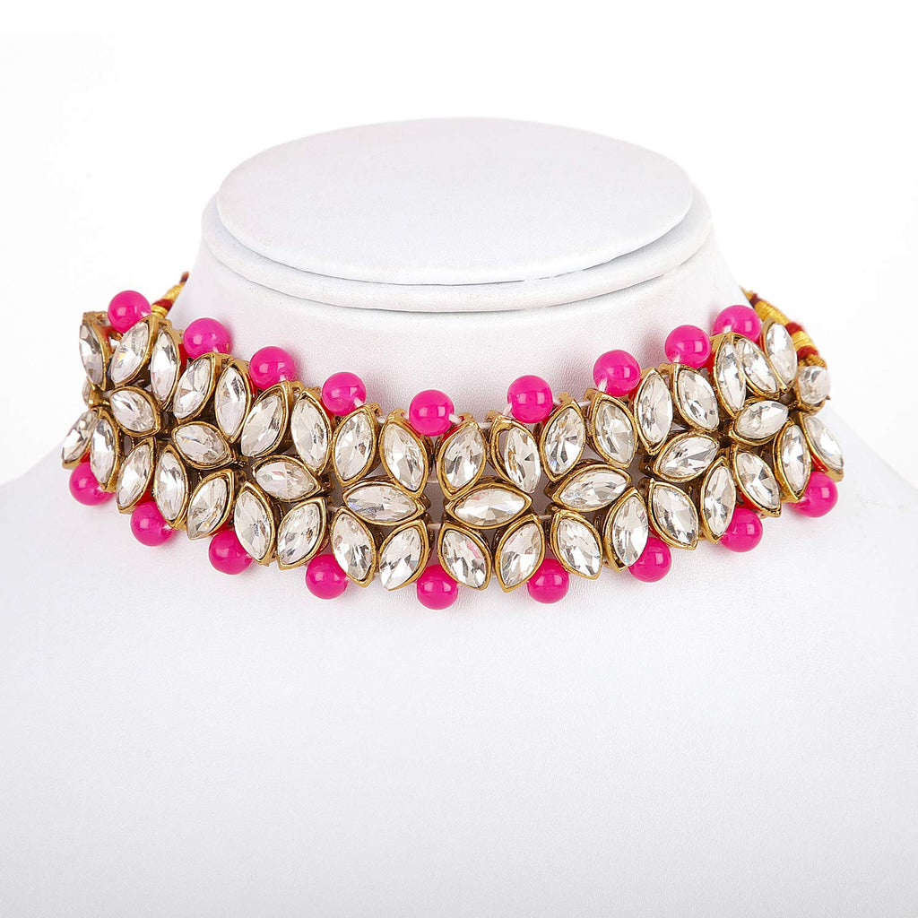 Necklace with pink beads and gold and crystal accents on a white stand