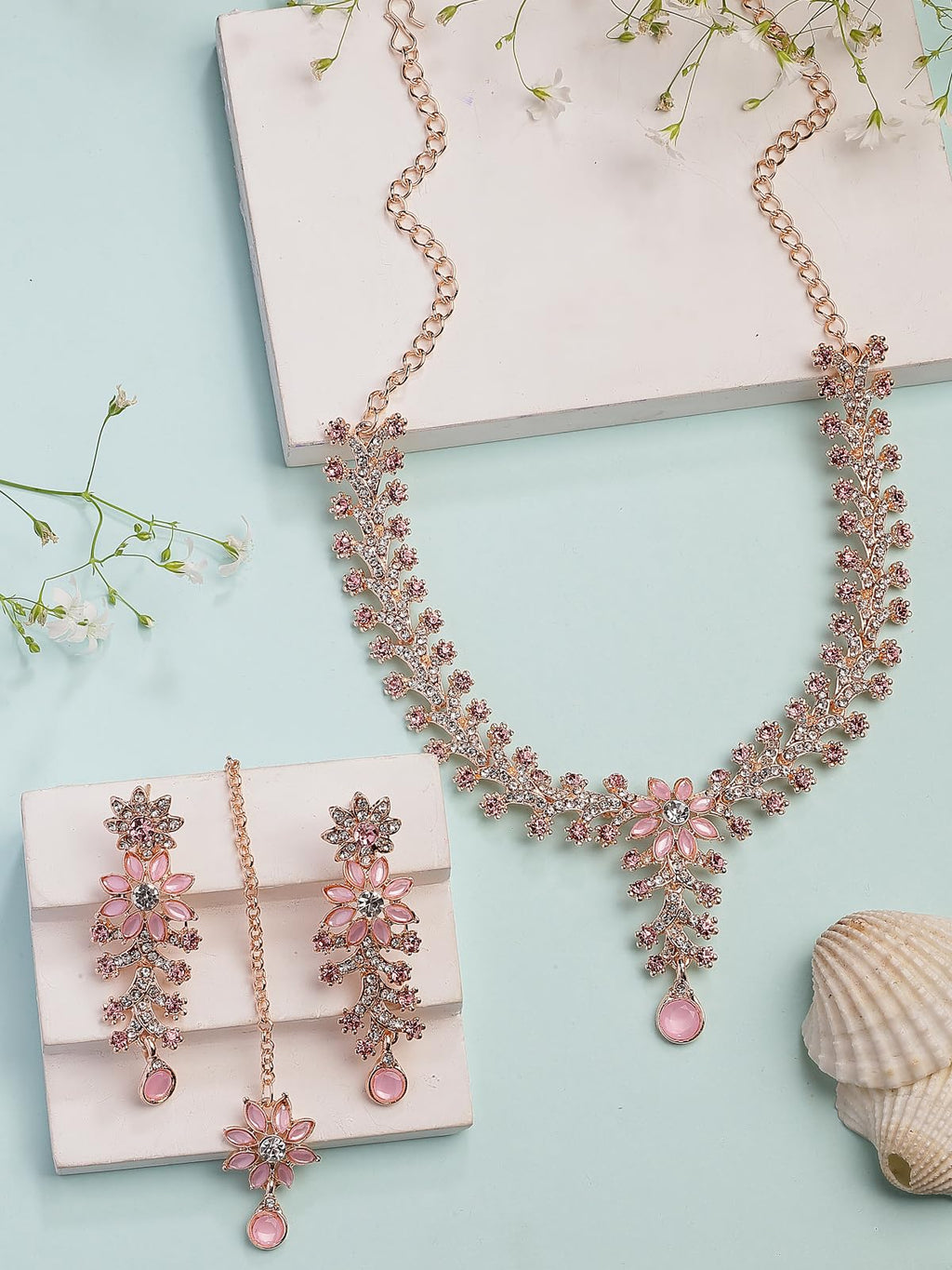 Pink jewelry set with necklace and earrings on a light blue background