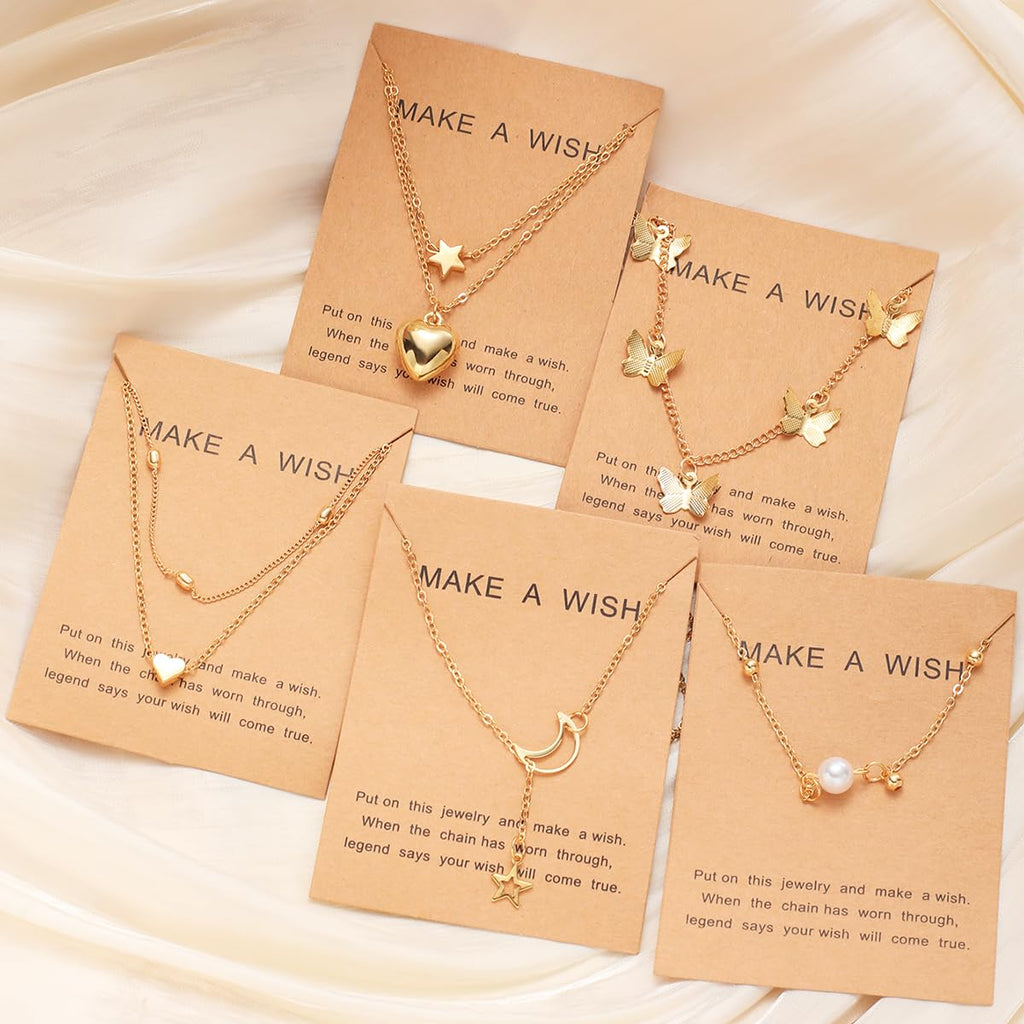 Set of gold necklaces on brown cards with 'Make a Wish' text, displayed on a beige fabric background.