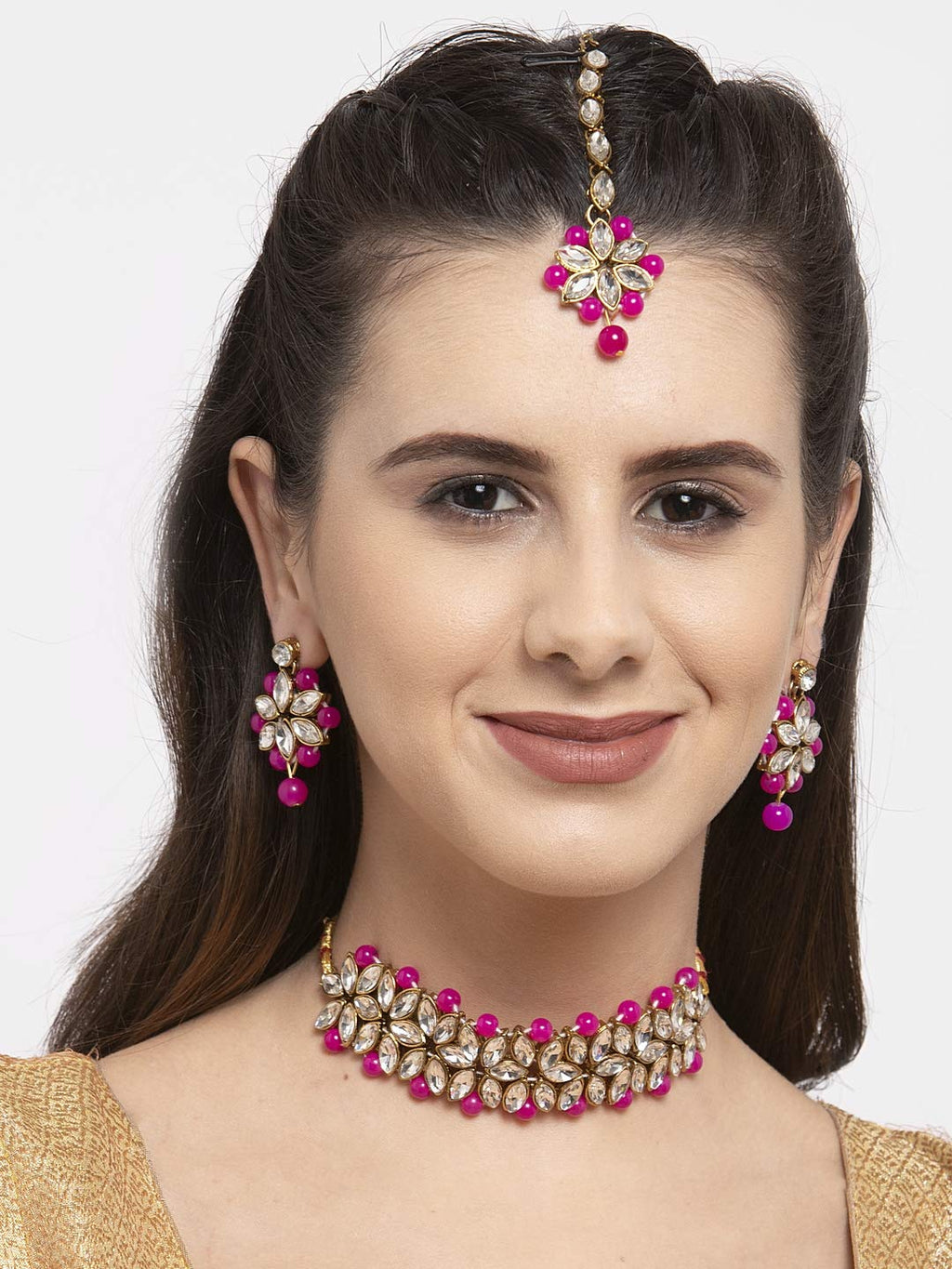 Woman wearing a pink and gold jewelry set with a white background