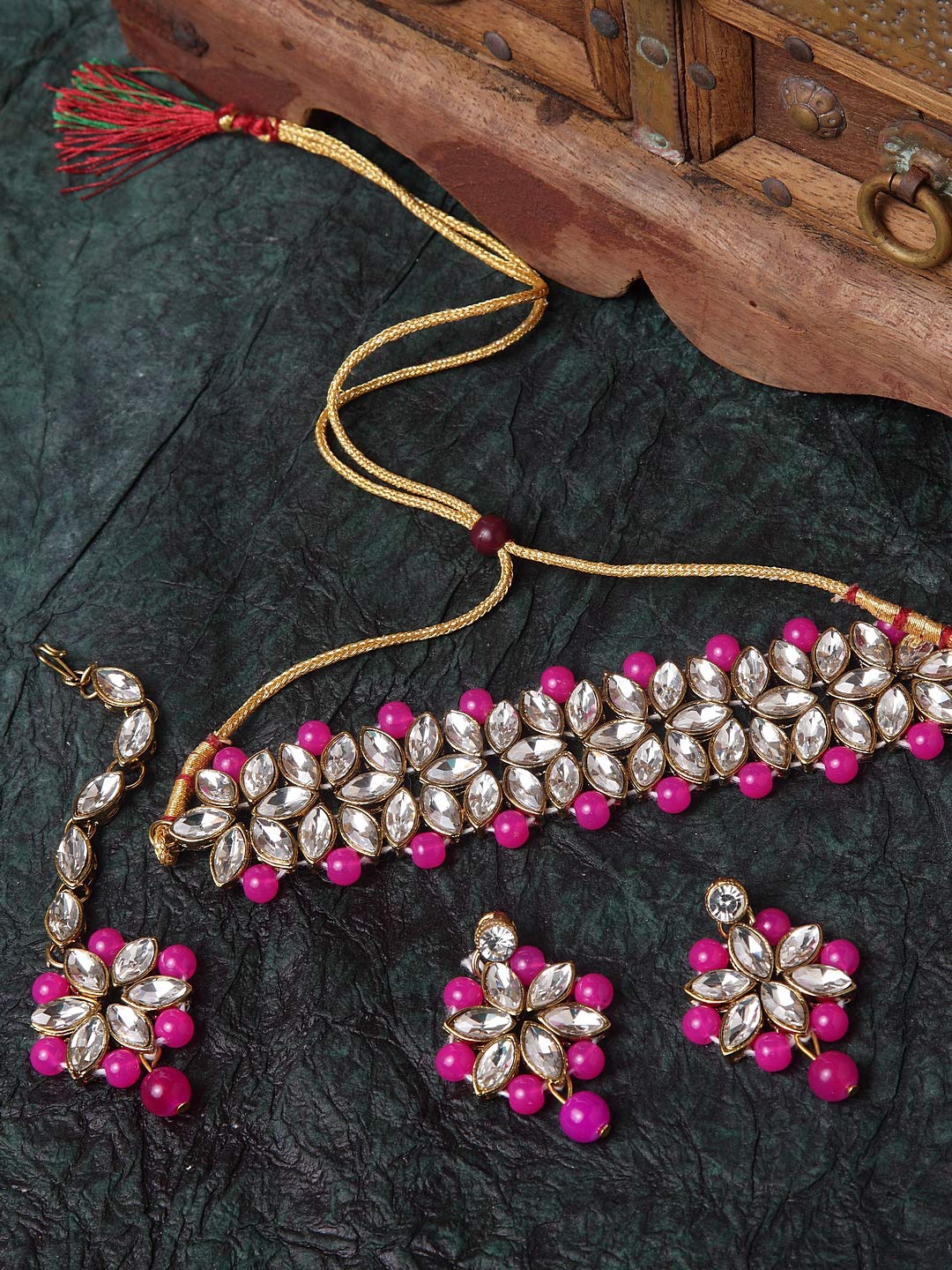 Jewelry set with pink beads and gold accents on a dark fabric background